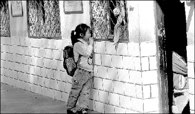 A 6-year-old girl listens to class outside the classroom window.