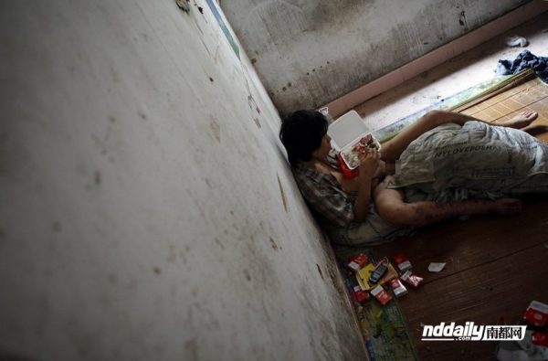 Wu Guilin, a drug addict in Guangdong province of China, lies half naked against the wall of his dilapidated home.