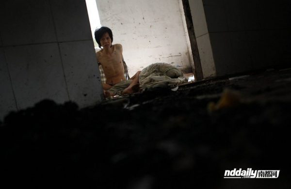 Wu Guilin, a drug addict in Guangdong province of China, shirtless and gaunt inside his dilapidated home.