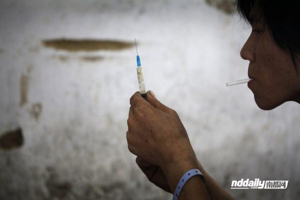Chinese drug addict Wu Guilin preparing to inject himself with heroin.