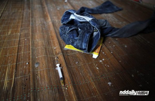 A pair of denim jeans and several drug needles remain in the deceased Wu Guilin's dirty room.