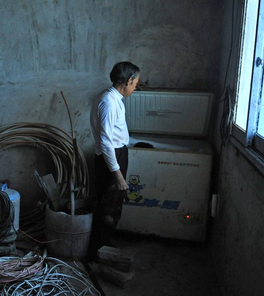 Tian Xueming, a father beside the freezer where he has kept his dead son's body frozen for the past 6 years, ever since his son died from leukemia.